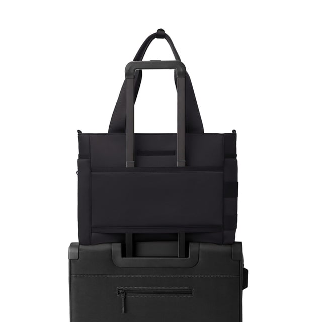 Dagne Dover large Wade Diaper Tote in black with the neoprene luggage sleeve attached to a suitcase handle.
